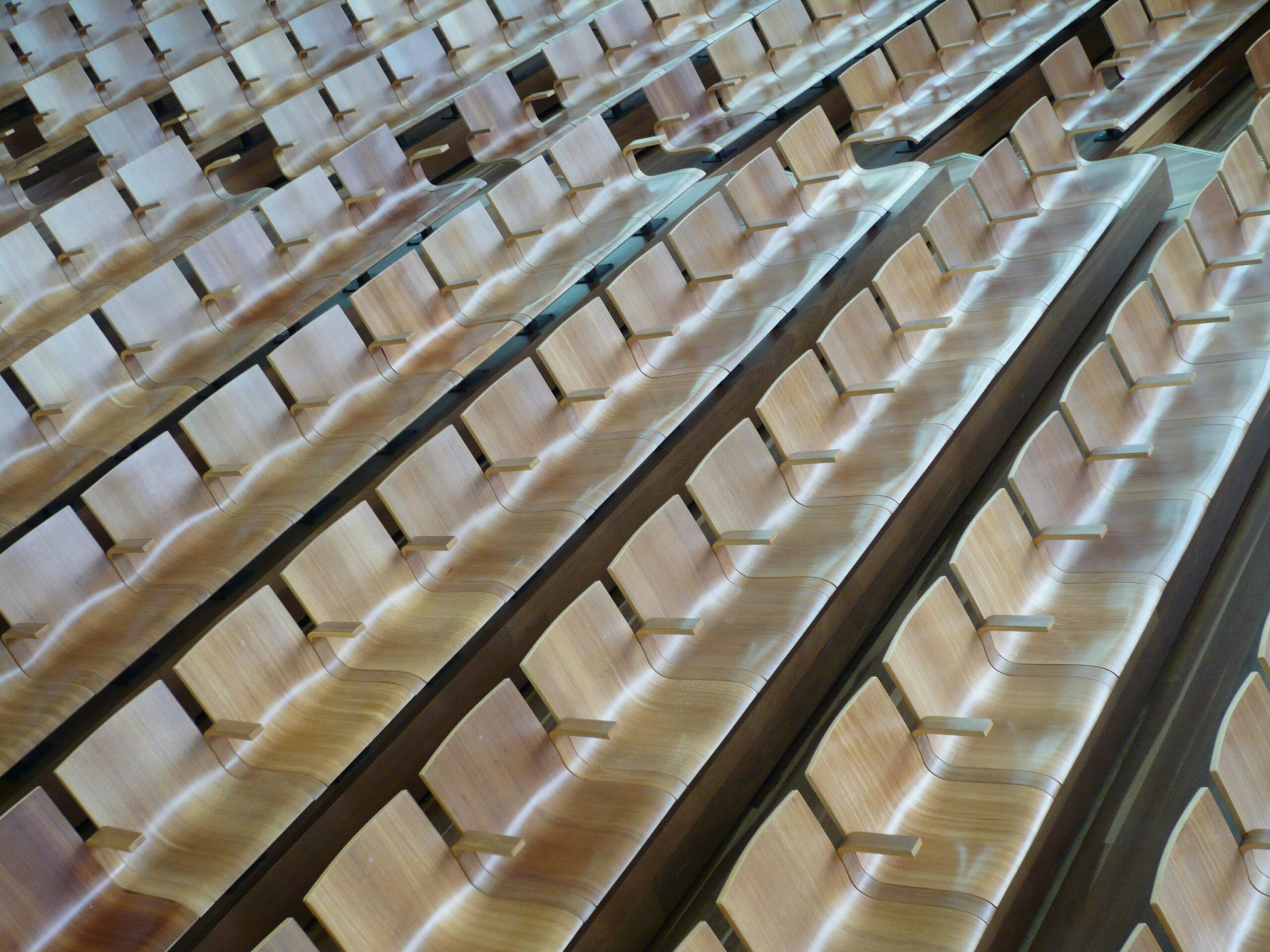 several rows of wooden chairs arranged in a lecture hall