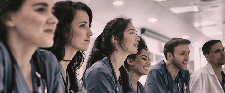 Diverse group of medical students in scrubs looking attentively during clinical training, showcasing future physicians engaged in medical education