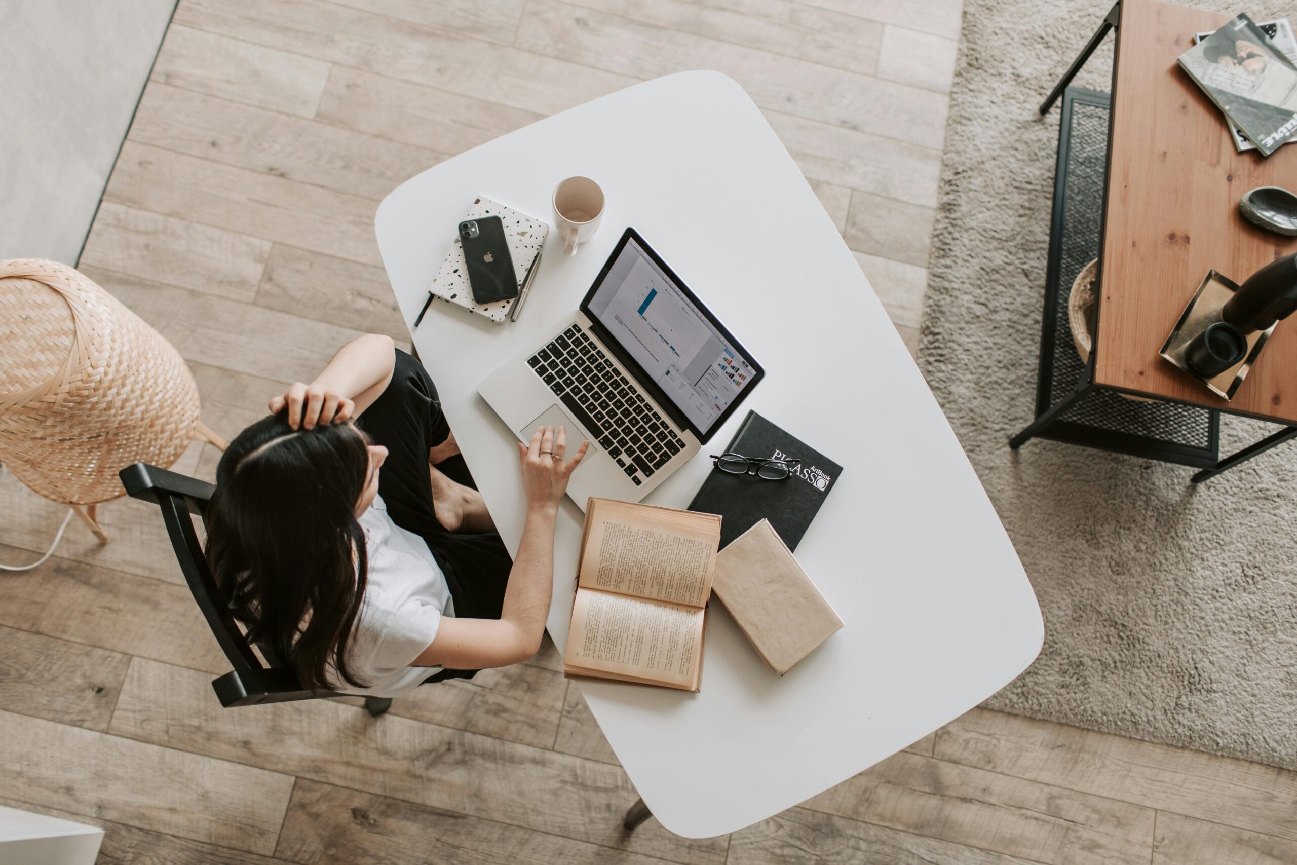 arial shot of woman at desk with laptop and papers scaled