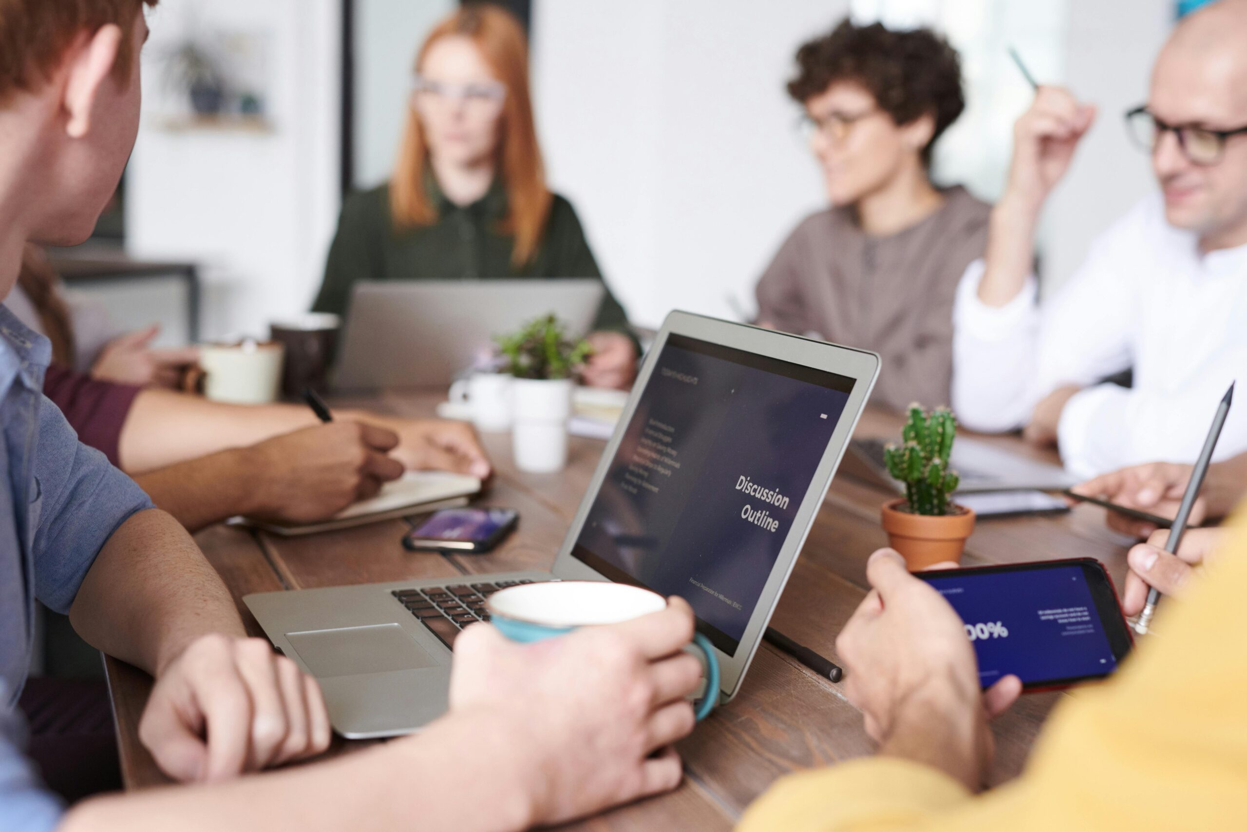 Group of people at conference table with laptops