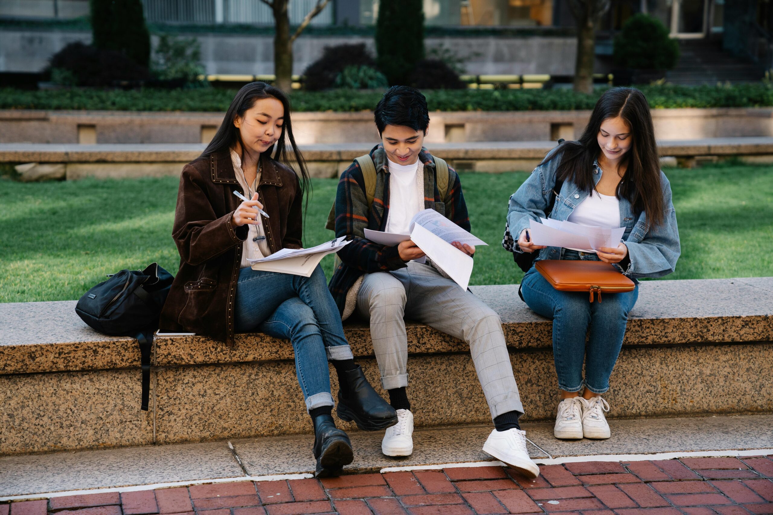 Three university students sitting on outdoor bench