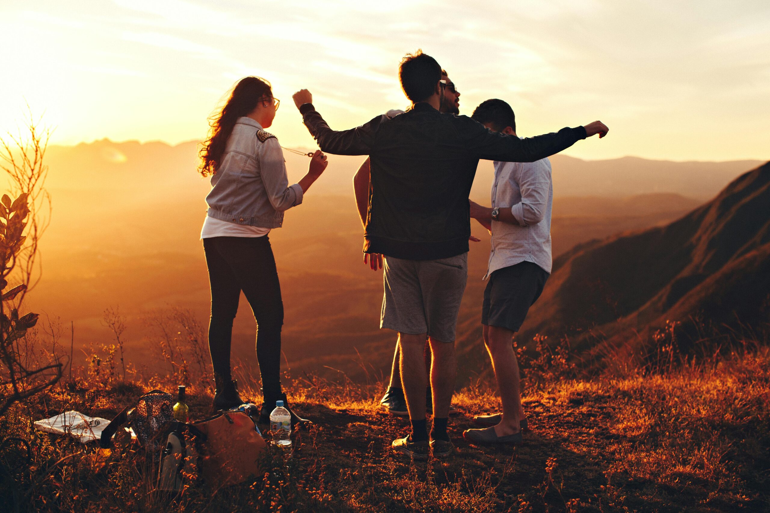 Group of young people on a hill lit by the golden light of sunset