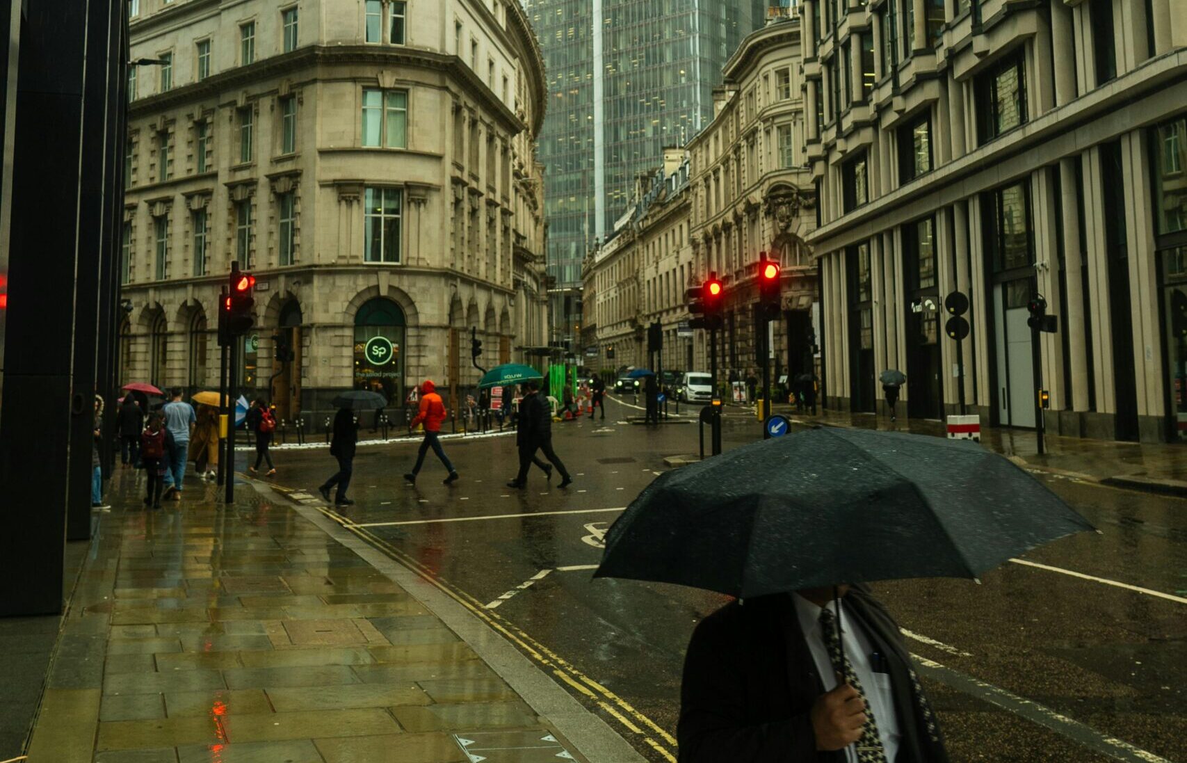 Man with umbrella covering face on busy London street