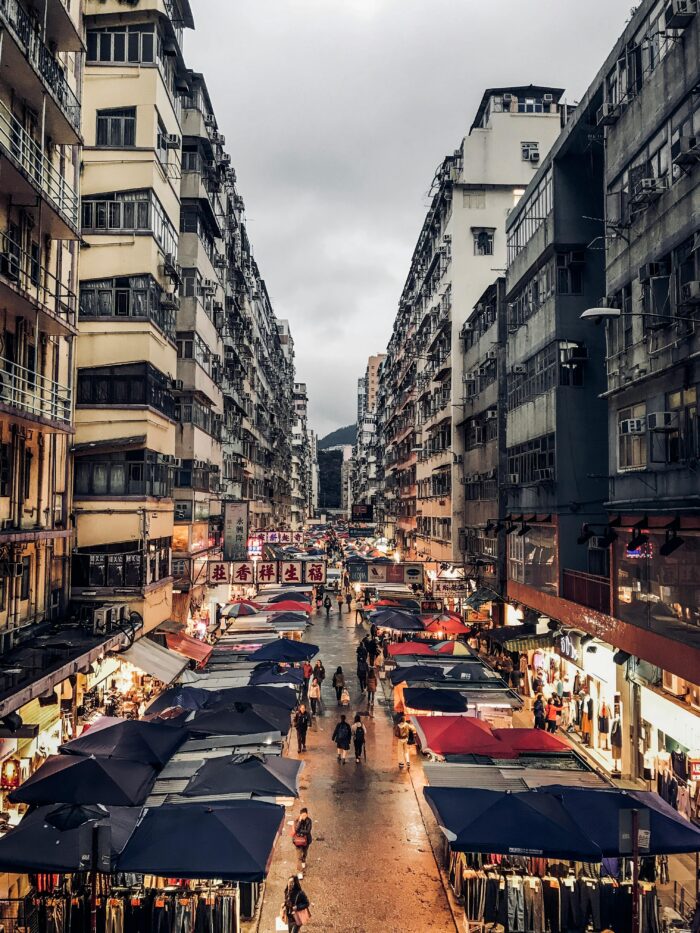 Photo of city street pathway between grey and black buildings in Hong Kong