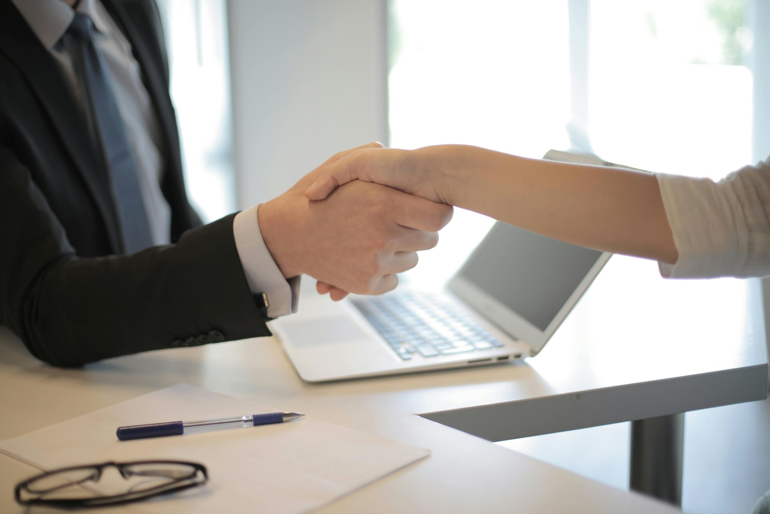 Two hands shaking over desk