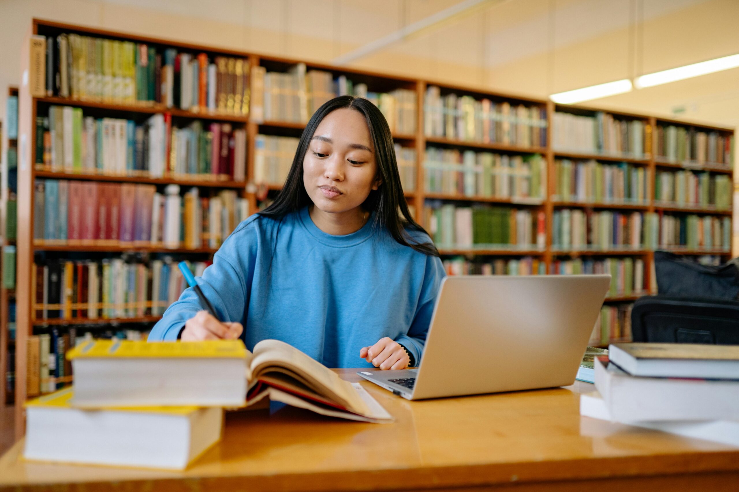 Young woman in blue sweater studying in library