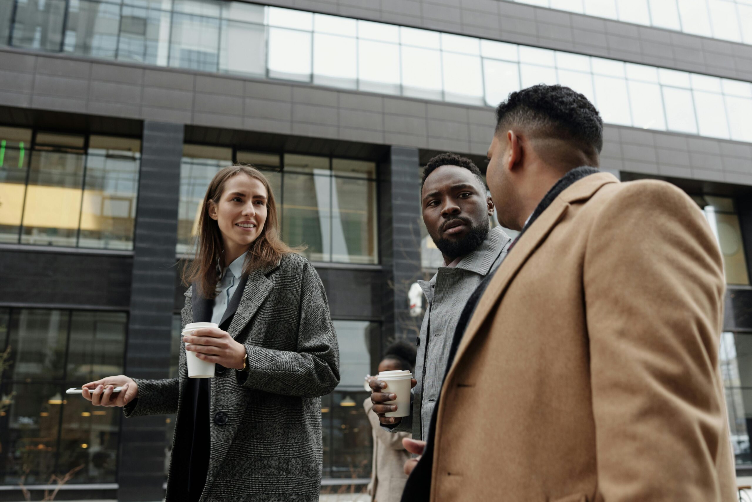 Three people in business attire walking down the street in conversation