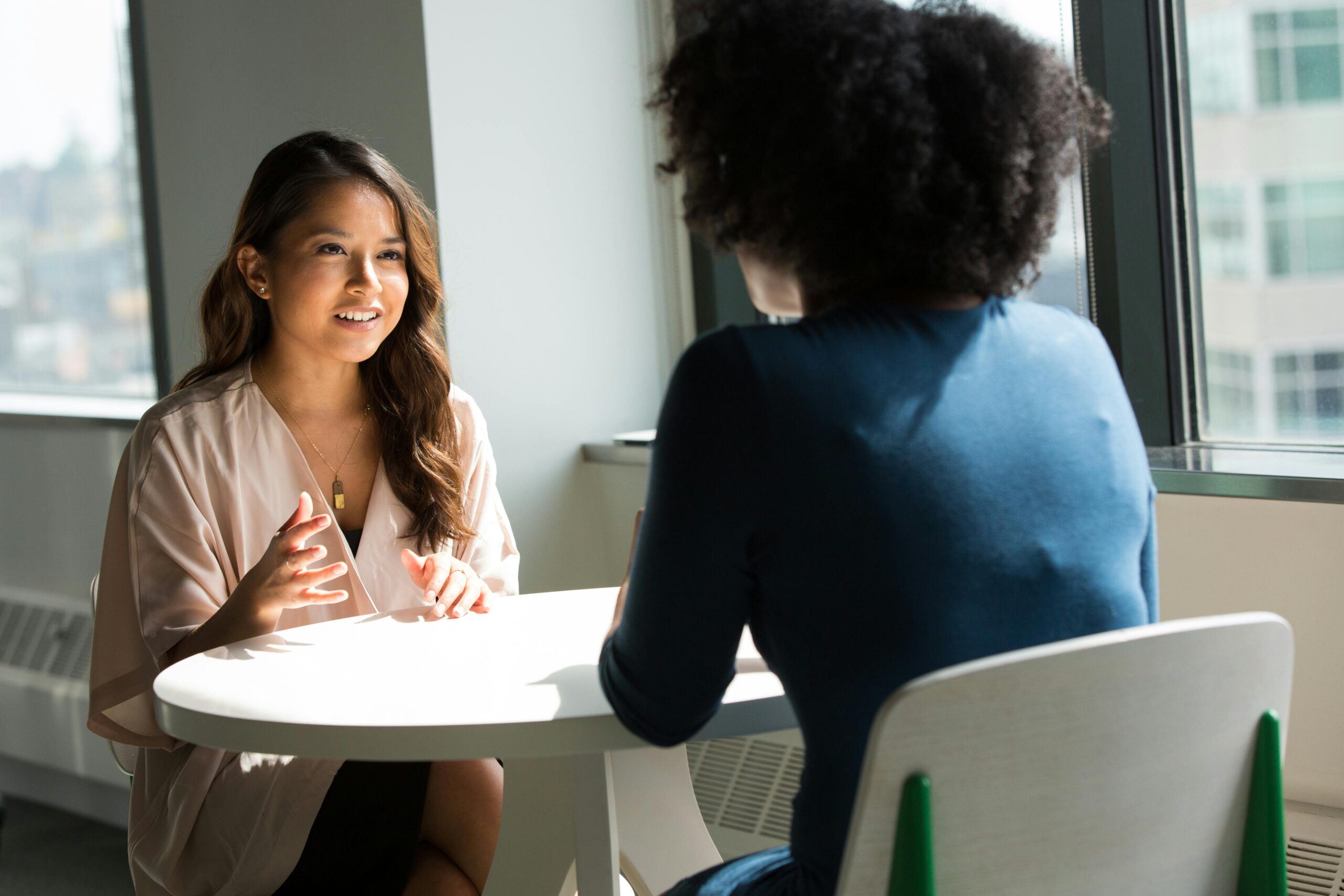 Two women in business attire discussing at a table
