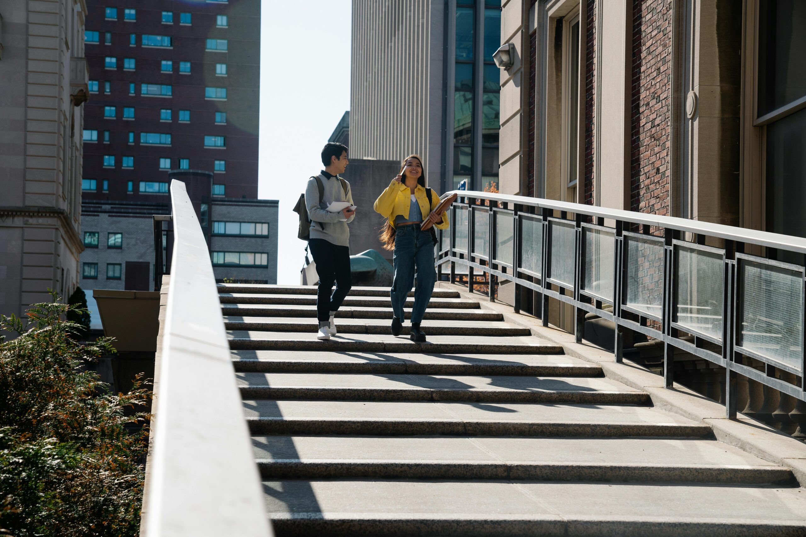 Two students in conversation walking down outdoor stairs