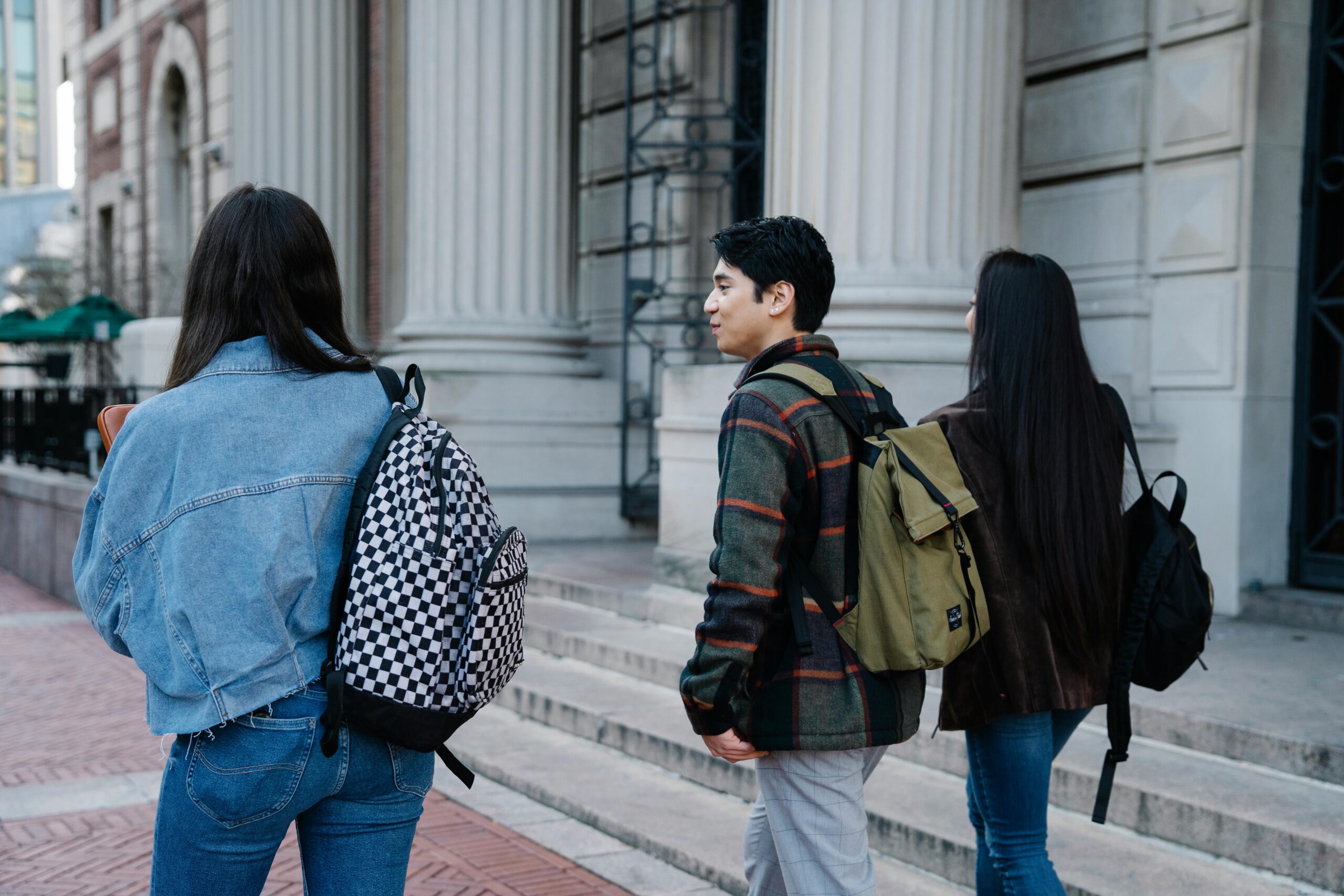 Three students walking past greek-style pillars
