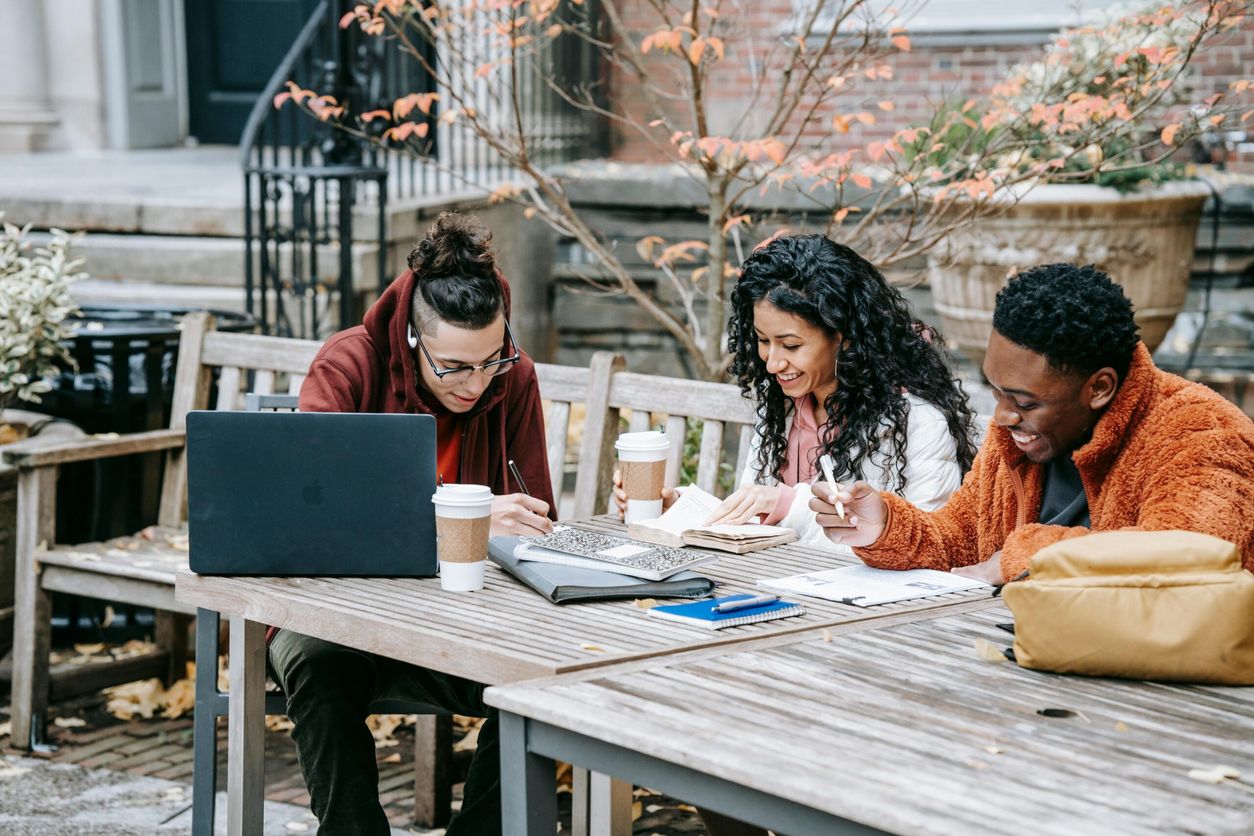 Three students studying at outdoor picnic table