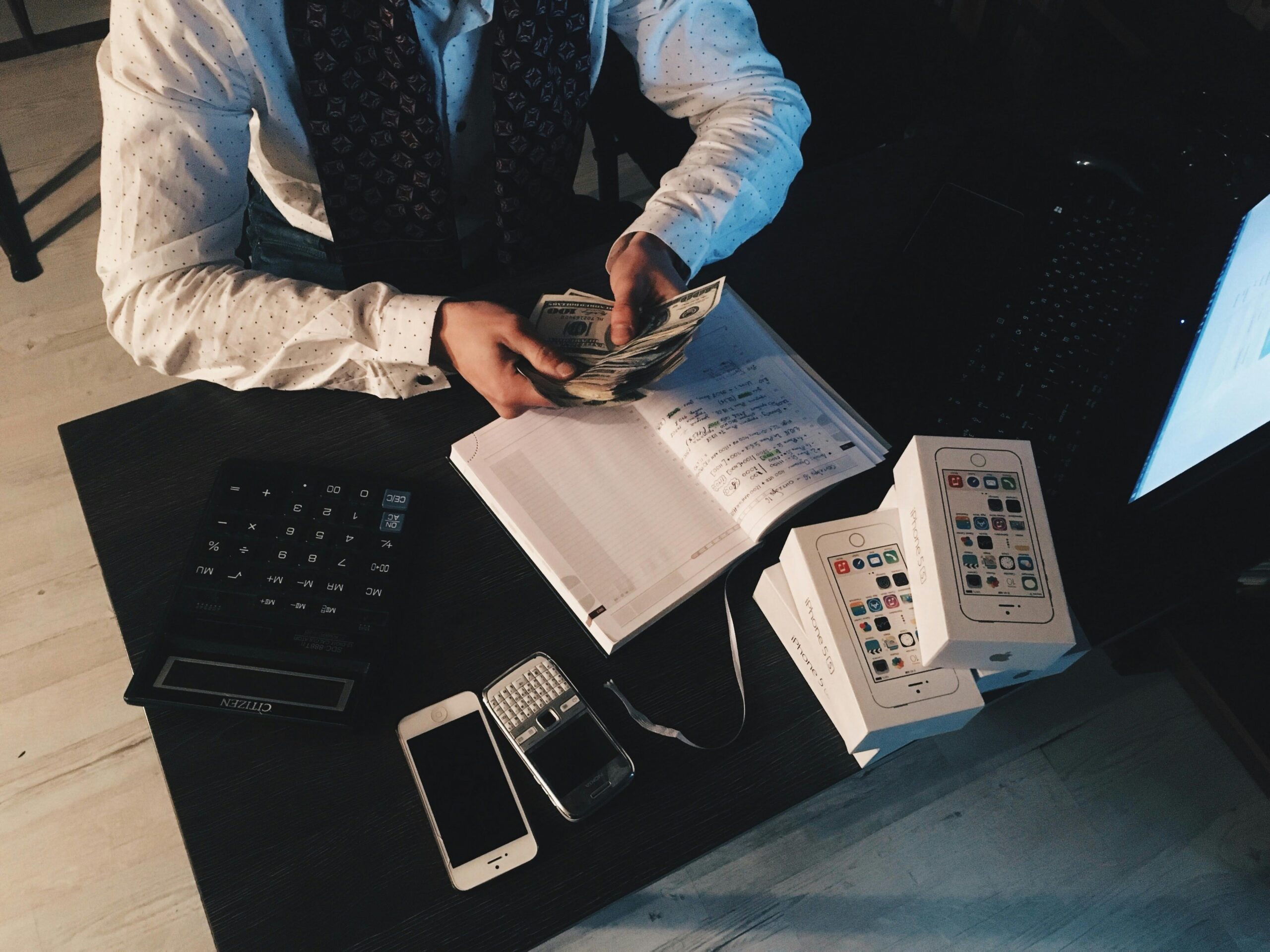 Man at desk holding dollar bills next to day planner