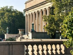Colmbia University Library - a greek style building with large stone pillars, illuminated by sunlight.