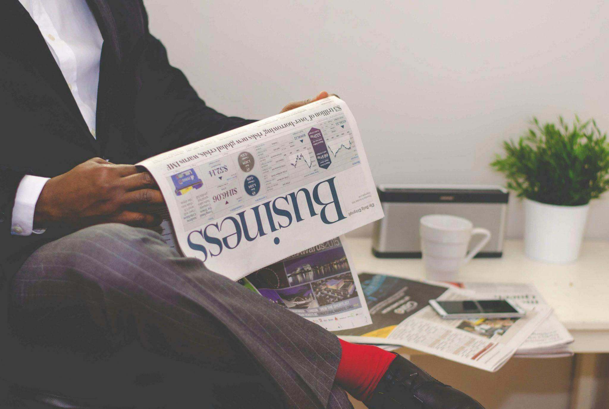 Man holding newspaper that says business in bold.