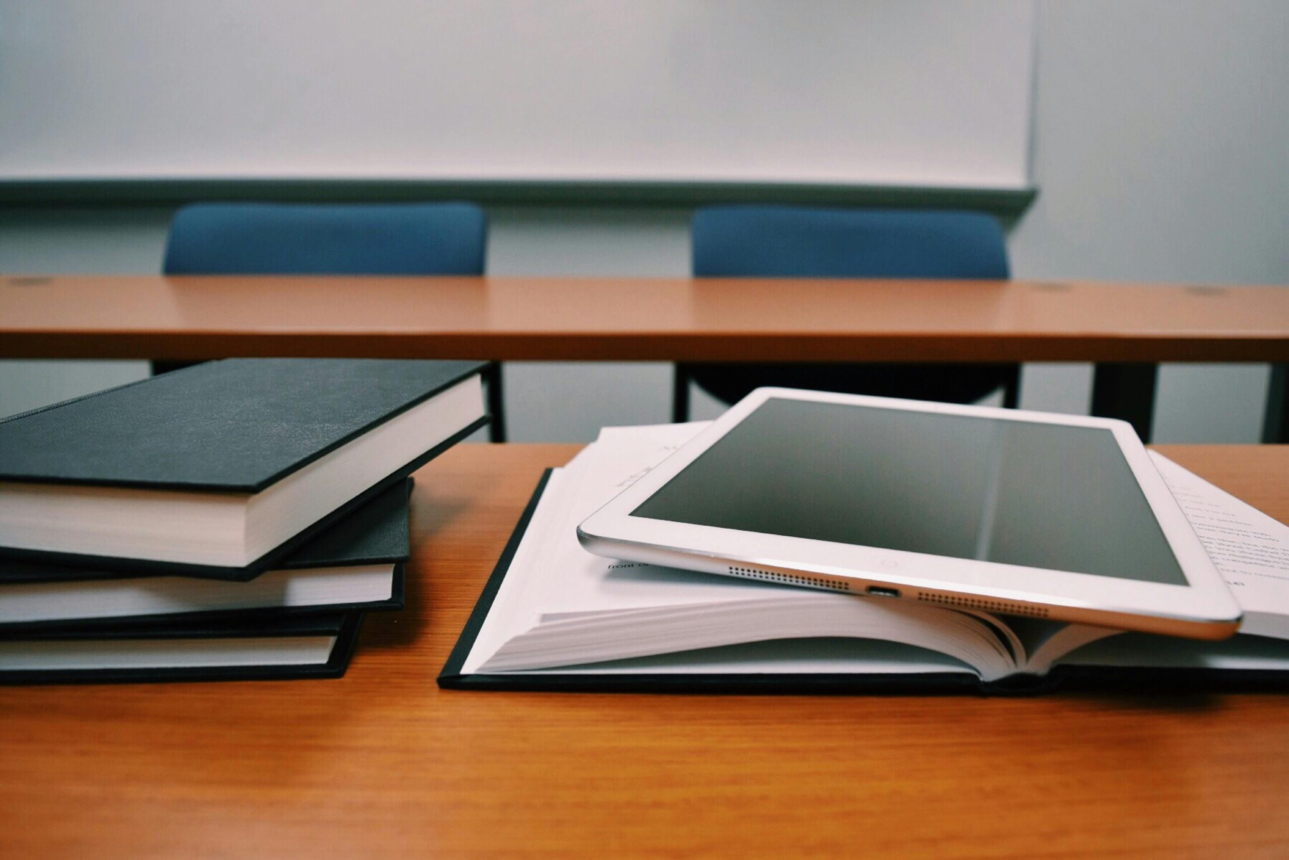 Books and a smart tablet on a wooden desk