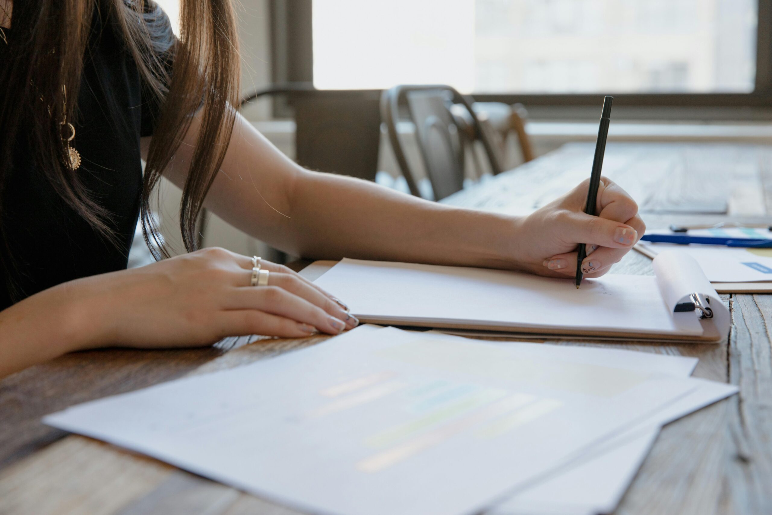 A Person in Black Shirt Writing on White Paper
