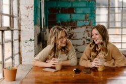 two women sitting at a table with drinks